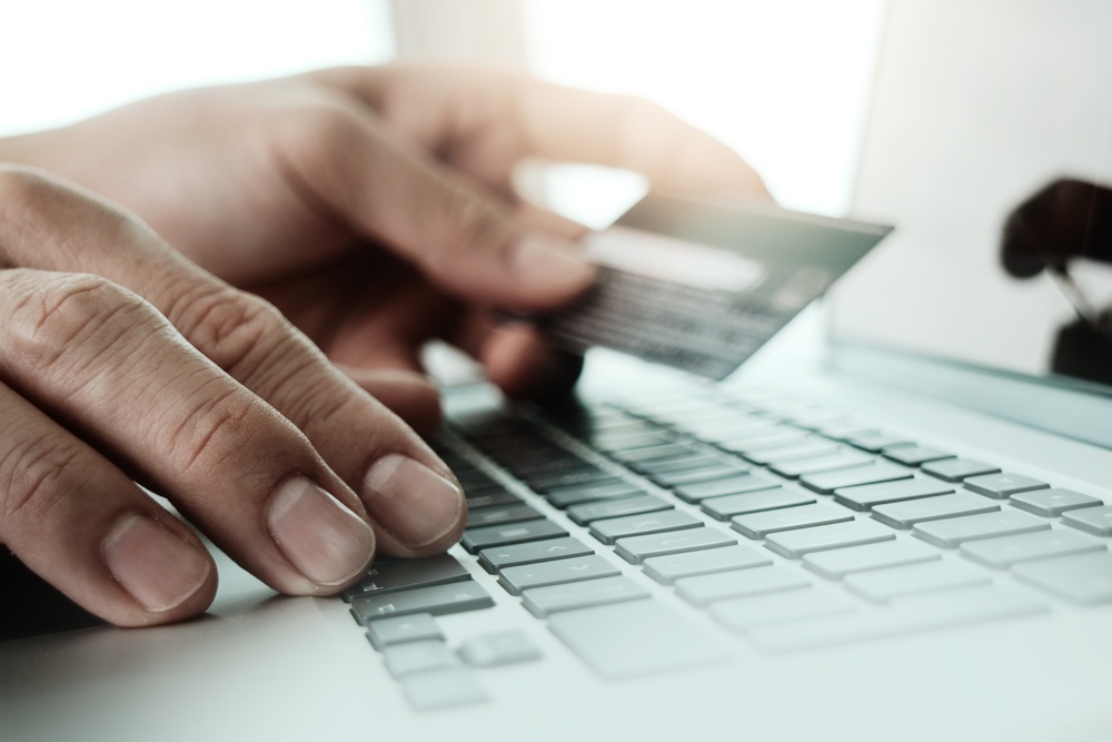 close up of hands using laptop and holding credit card as Online shopping concept